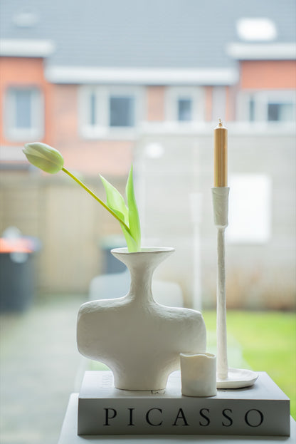 Gebroken witte vaas met tulp op een boekenstapel bij het raam